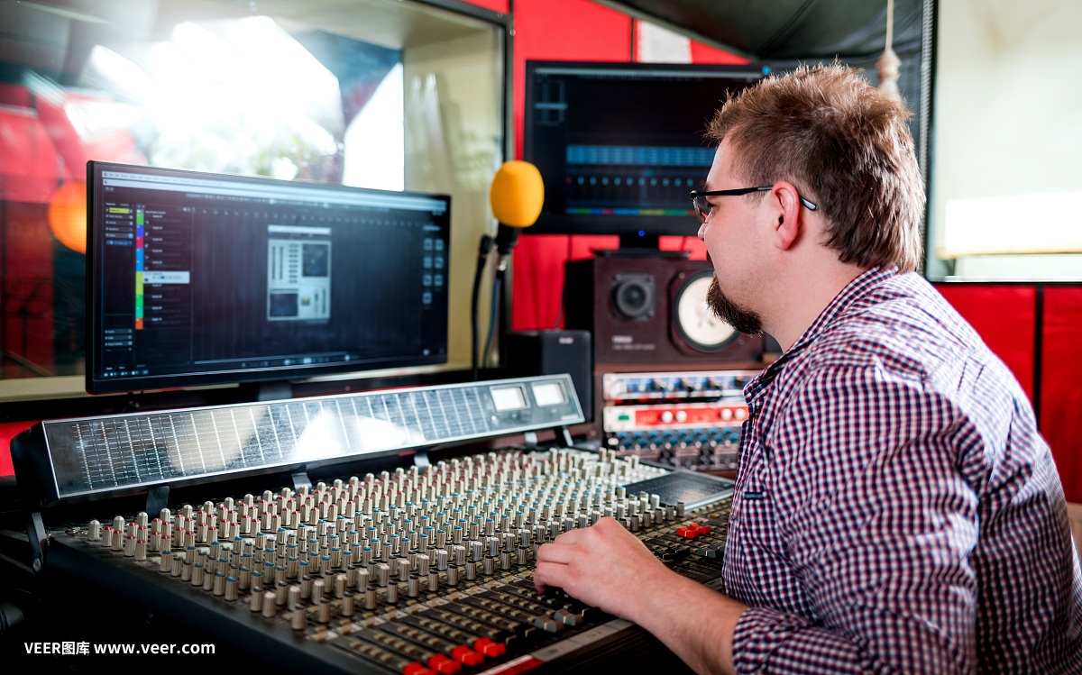 聲音制作人在錄音棚使用音板和監(jiān)視器工作